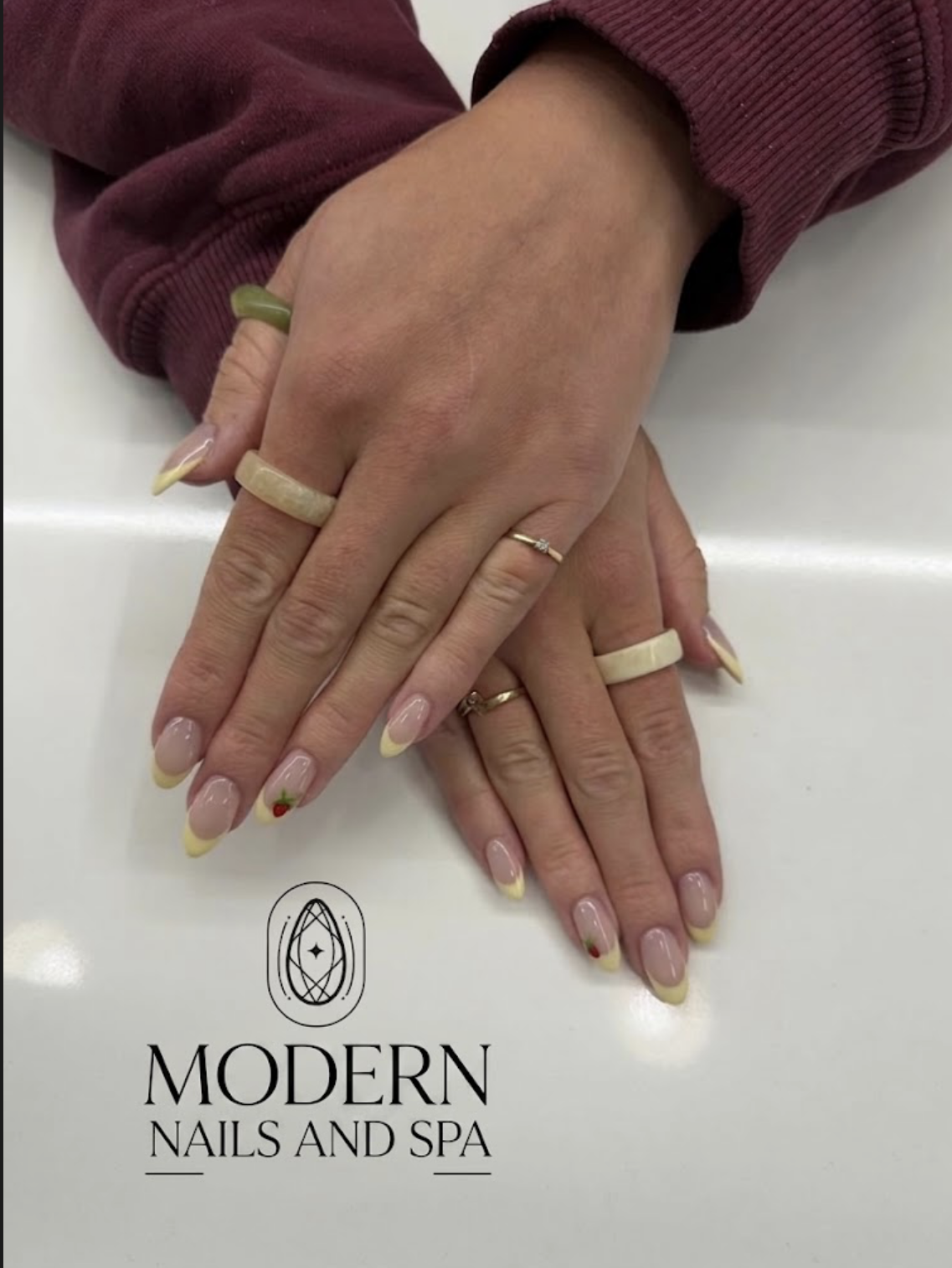 Soft yellow French tip almond nails with tiny strawberry art